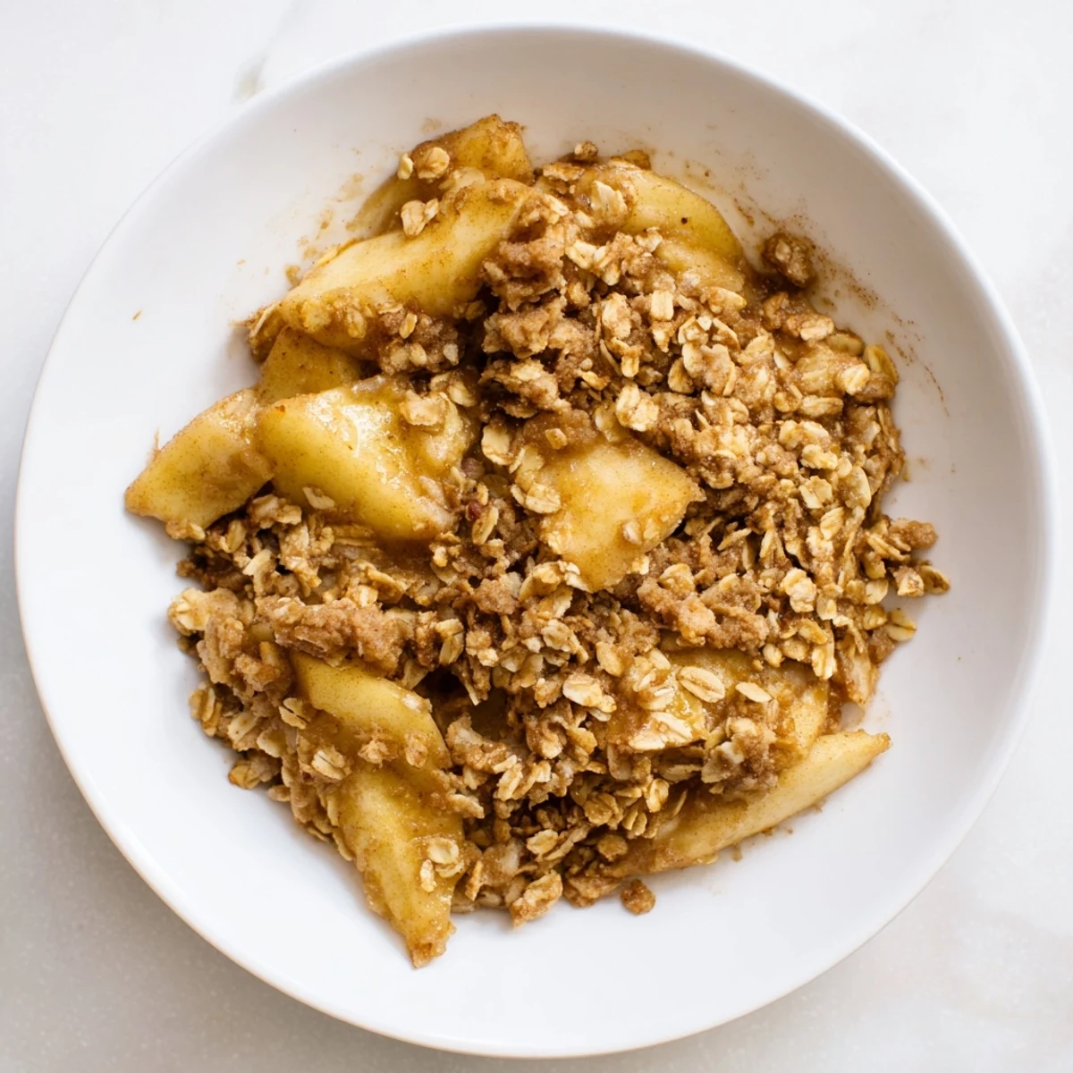 A close-up of bubbling apple crisp, showing the tender fruit and crispy oat crumble topping.