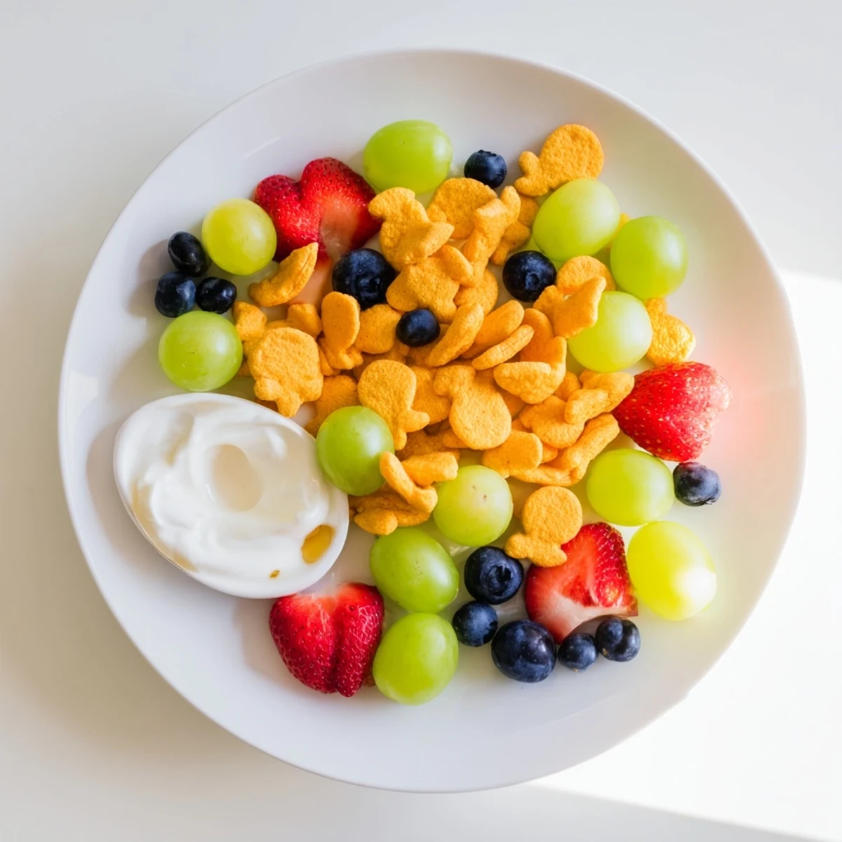 Vibrant pile of rainbow Goldfish crackers with colorful fruits; a perfect kid-friendly snack.