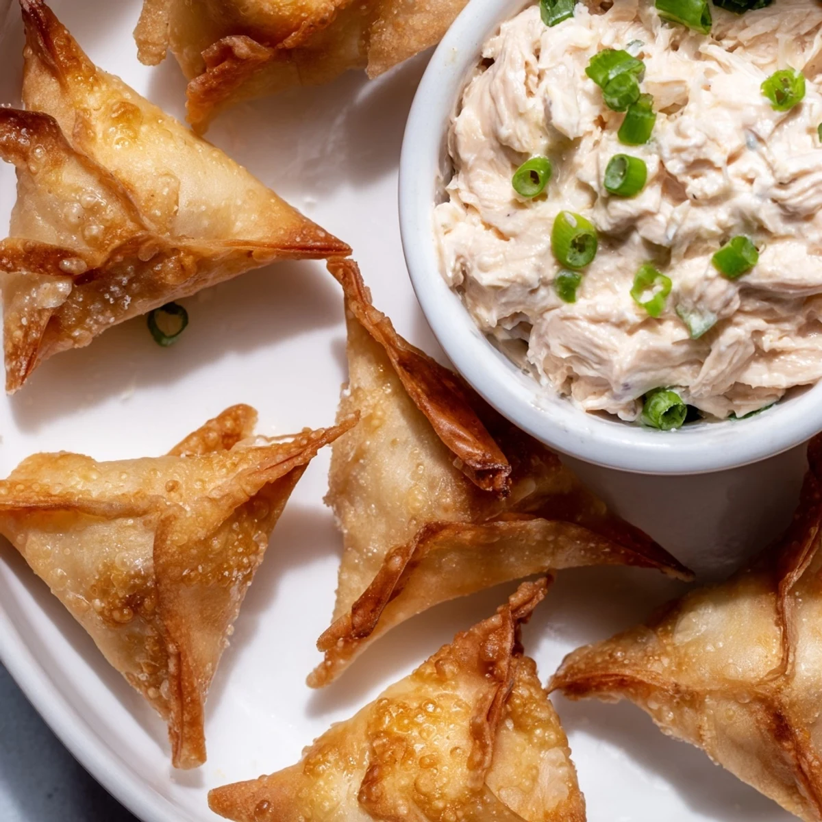 A close-up view of fresh-made air fryer lumpia chips, paired with a vibrant chicken cream cheese dip.