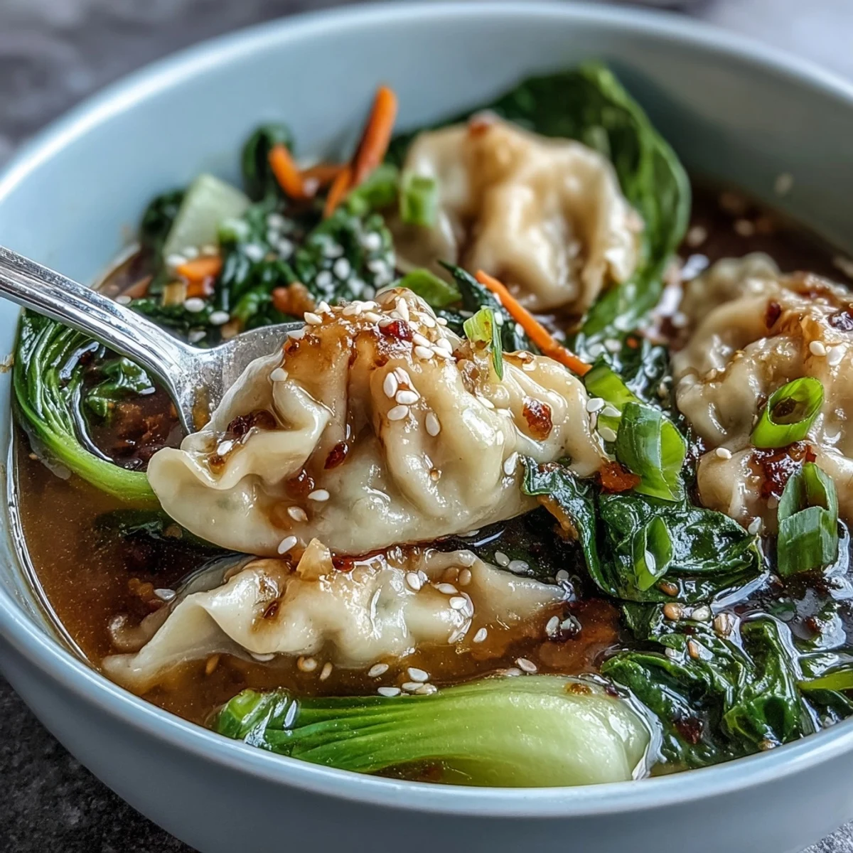 A steaming bowl of Asian dumpling soup with tender dumplings, crisp bok choy, and fragrant ginger in a savory broth.