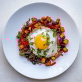 Vibrant skillet of sweet potato and black bean breakfast hash, topped with perfectly cooked eggs and cilantro.