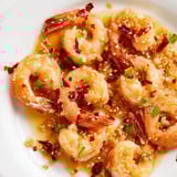 A close-up of delicious Korean Garlic Butter Shrimp, garnished with scallions and sesame seeds.