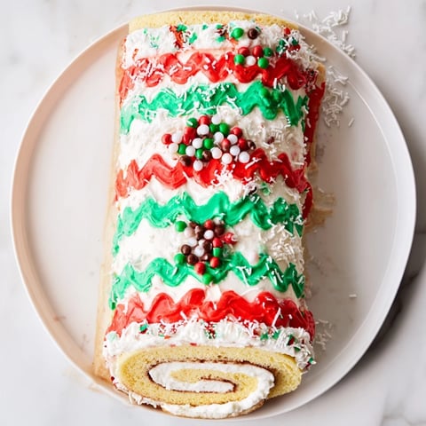 Ugly Sweater Cake Roll, a festive dessert, frosted with red and green designs and holiday sprinkles.