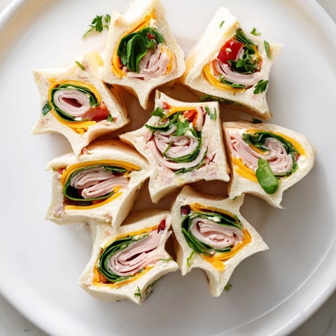 Beautiful star-shaped party sandwiches featuring deli meats, cheeses, and fresh spinach inside.