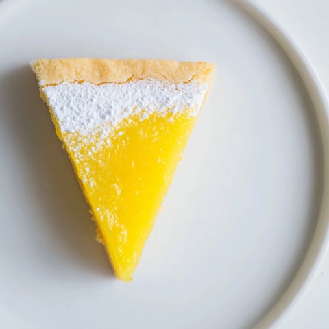Golden, triangular lemon bars dusted with powdered sugar, ready to be enjoyed as a sweet dessert.