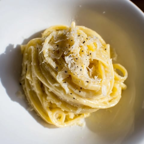 Steaming bowl of Lazy Girl Three-Ingredient Pasta, coated in creamy Parmesan and butter sauce.