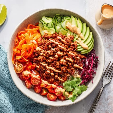 Savory plant-based meat bowl garnished with avocado, cilantro, and lime wedges.  
