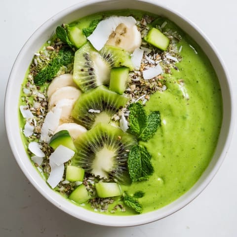 Creamy green smoothie bowl featuring fresh kale, avocado, and kiwi, a delightful vegan breakfast ready to eat.