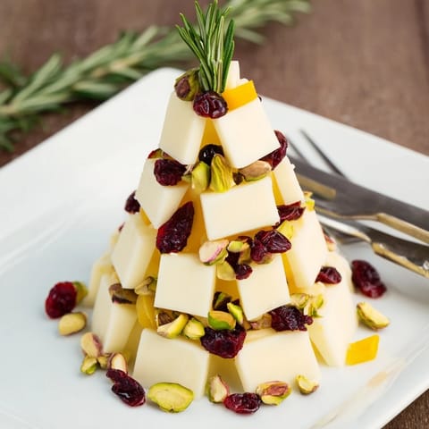 A beautiful holiday photo of a cranberry white cheddar tree featuring red cranberries and green rosemary sprigs.