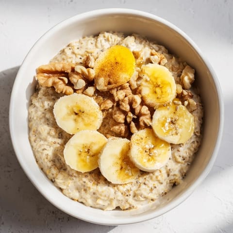 Warm, creamy Microwave Banana Oats topped with fresh banana and crunchy walnuts for breakfast.