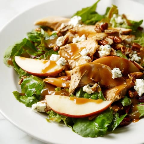 Vibrant autumn Caramel Apple Chicken Salad topped with crumbled feta, dried cranberries, and a glossy caramel-pecan dressing drizzle.  