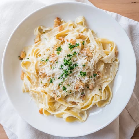 Golden roasted garlic pasta in a creamy sauce, served in a rustic white bowl.