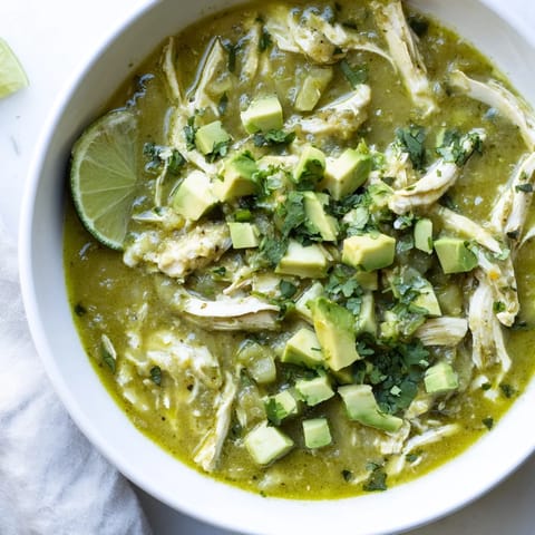 A steaming bowl of Chicken Chili Verde served over cilantro rice, with warm corn tortillas on the side.
