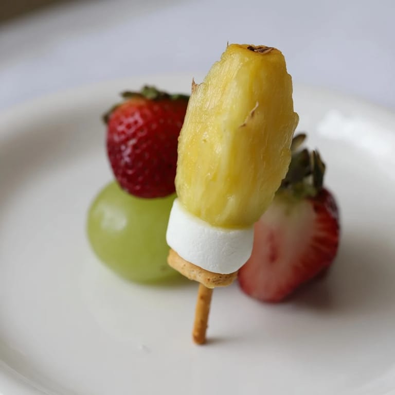 Vibrant Christmas Light fruit skewers featuring strawberries, grapes, and pineapple, arranged like festive lights.