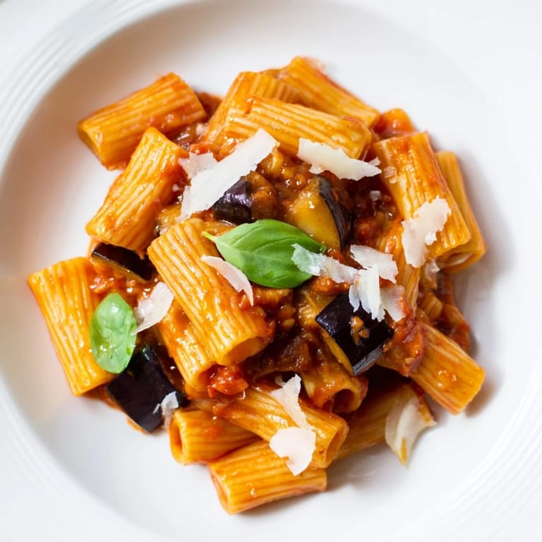 Pasta Alla Norma, a classic Sicilian main dish, served in a rustic bowl with fresh basil and ricotta salata.  