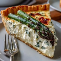 Asparagus Ricotta Tart with a flaky puff pastry base, creamy cheese filling, and fresh asparagus spears, perfect for a light spring meal.